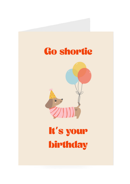 Birthday card with a dog holding balloons and text on a beige background